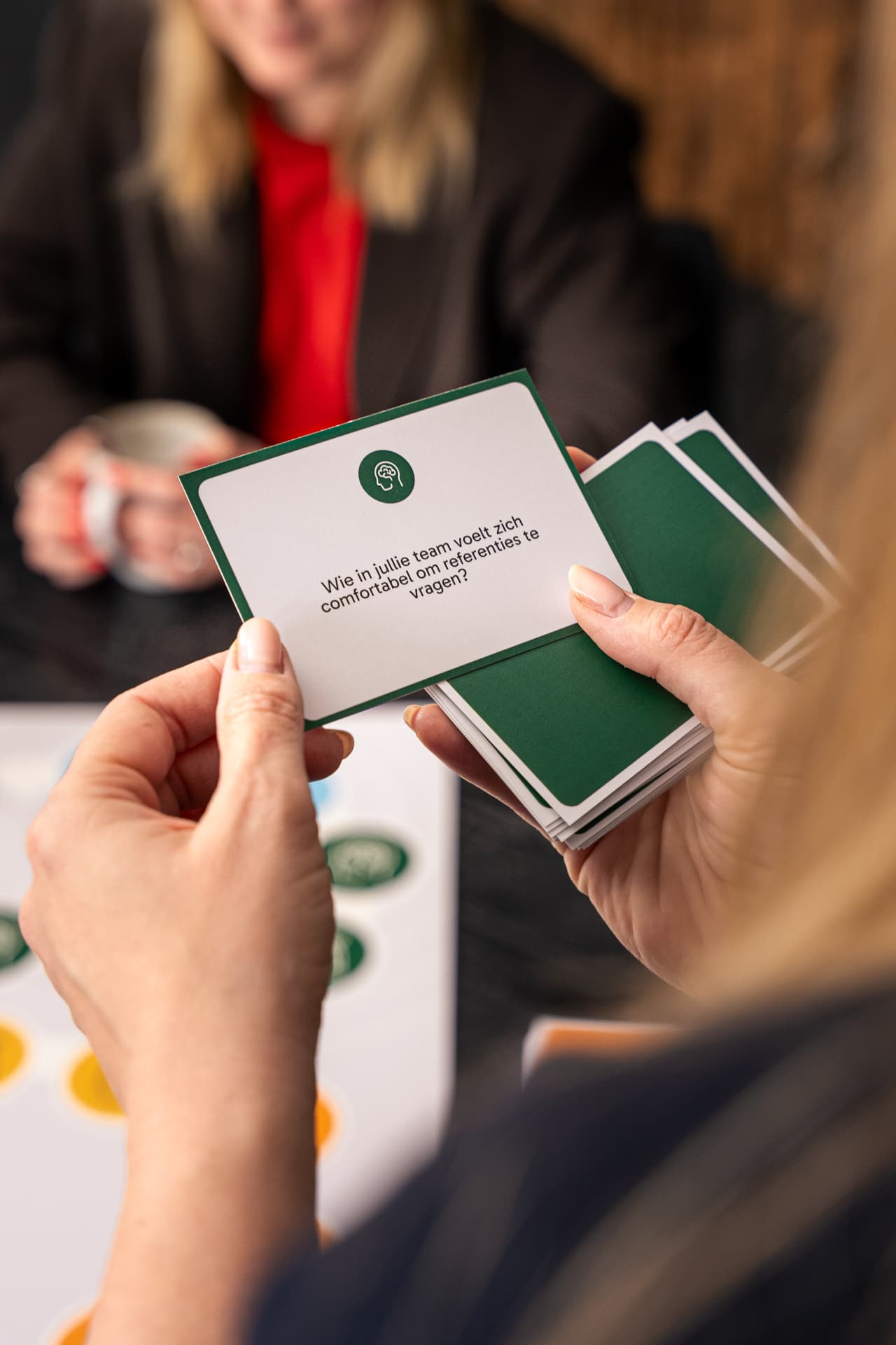 Speelster houdt een reflectiekaart omhoog met de vraag: Wie in jullie team voelt zich comfortabel om referenties te vragen?